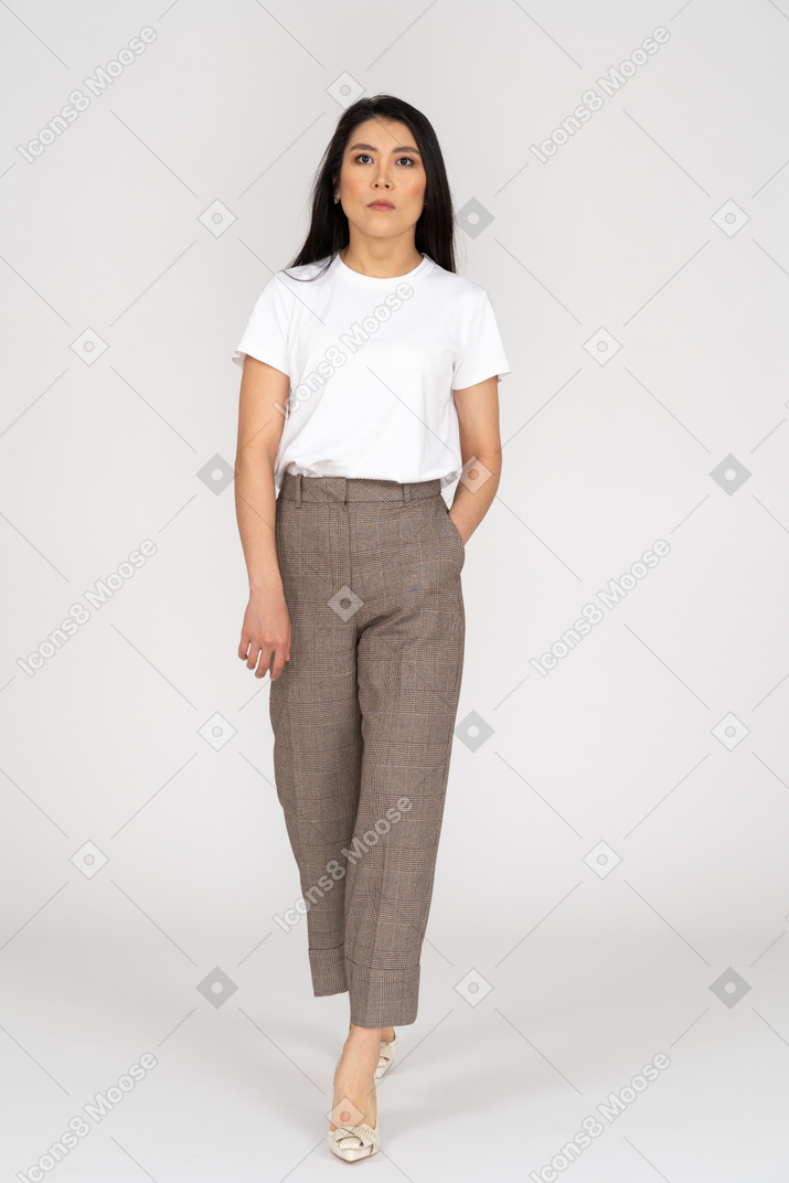 Front view of a serious young woman in breeches putting hand in pocket