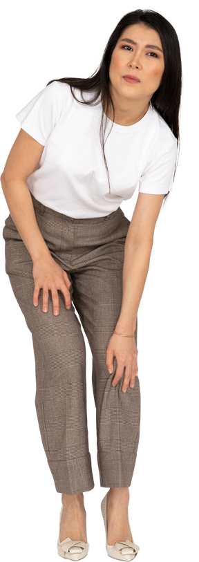 Vista laterale di una giovane donna in calzoni e t-shirt protesa in avanti