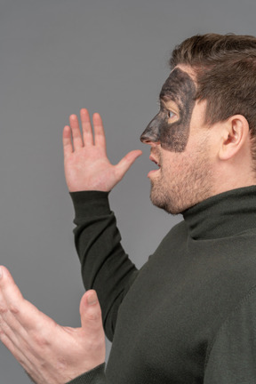 Side view of an astonished male football fan raising hands