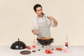 Giovane uomo caucasico con un assaggio di barbecue sta cucinando