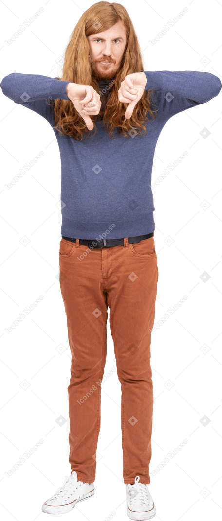 Vista frontal de un joven con ropa informal que muestra los pulgares hacia abajo y mira la cámara