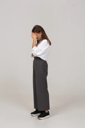 Side view of an upset young lady in office clothing hiding face