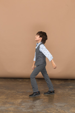 Vista laterale di un ragazzo in abito grigio che cammina