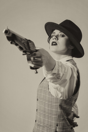 Confident woman in hat aiming the gun with one hand