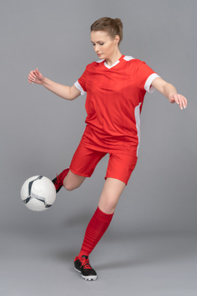 A sporty female player is about to kick the ball