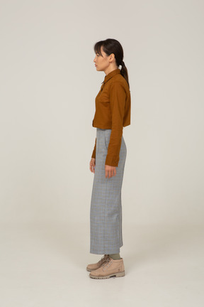 Side view of a puzzled young asian female in breeches and blouse standing still