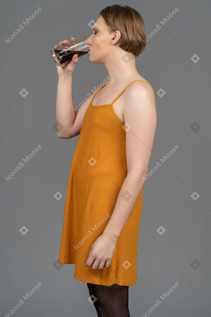 Side view of a non-binary person in a dress having a drink