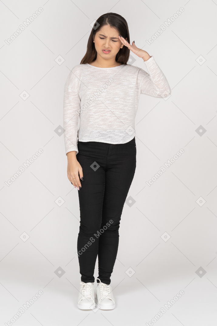 Front view of a young indian female in casual clothes with a headache
