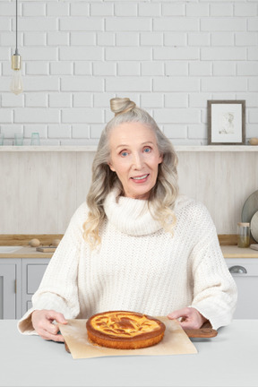 A woman in a white sweater is holding a pie