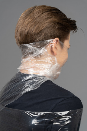 Rear view of a young man wrapped in plastic