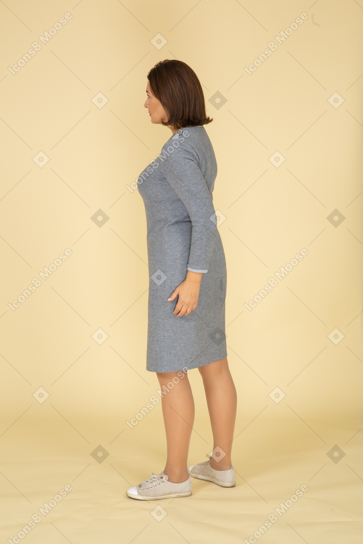 Вид сбоку женщины в сером платье