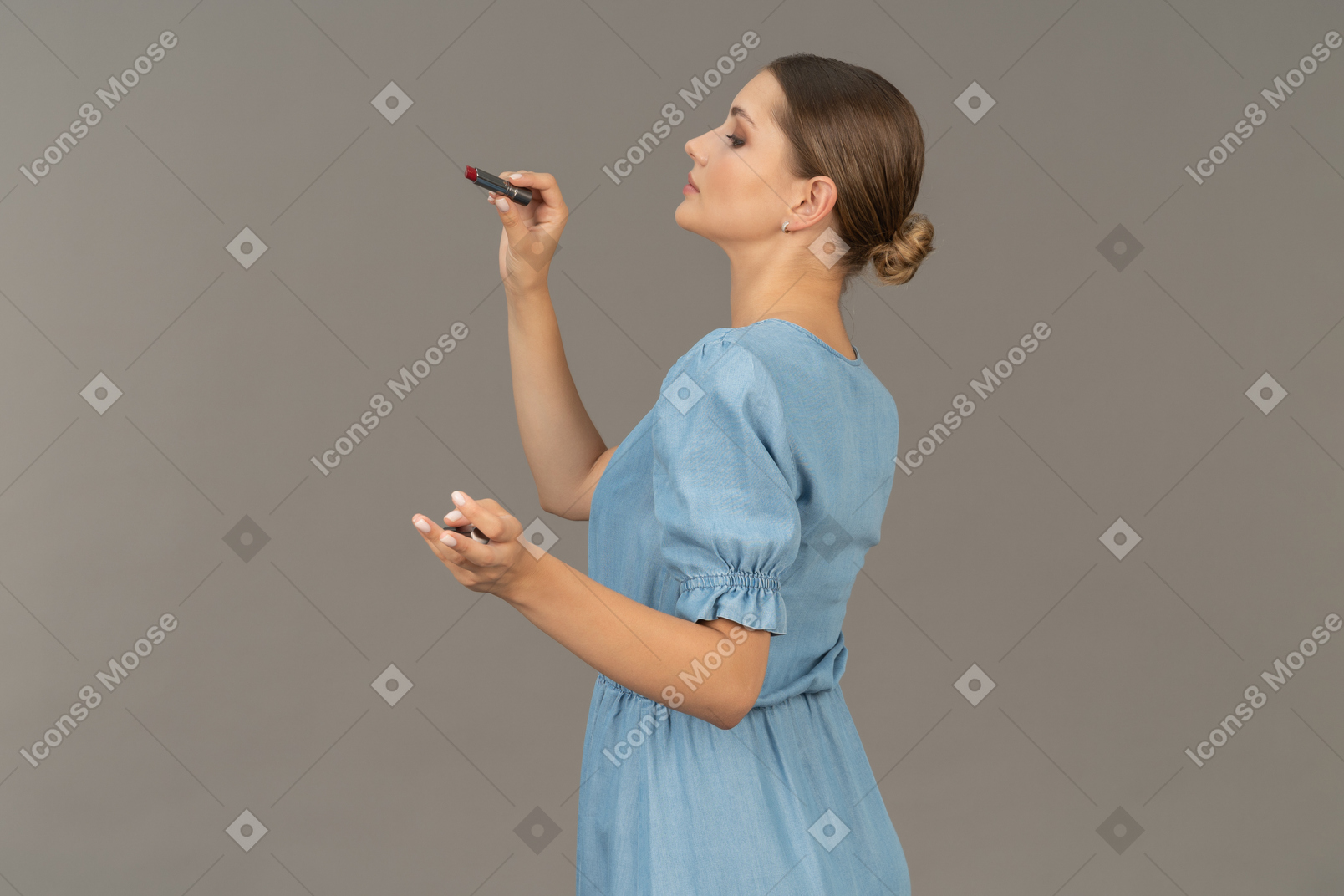 Side view of a young woman in blue dress holding a lipstick