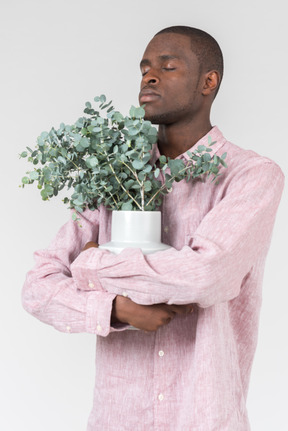 Beau jeune homme avec une plante en pot