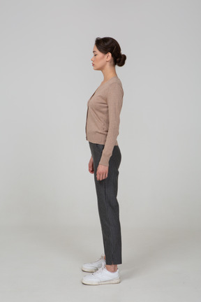 Side view of a young lady standing still in pullover and pants with her eyes closed
