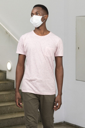 A man wearing a face mask while standing in front of stairs