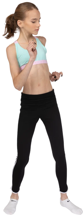Front view of a teen girl in sportswear dancing and raising her arm