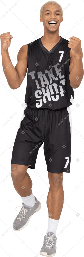 Vista frontale di un giovane giocatore di basket maschio felice che alza le mani