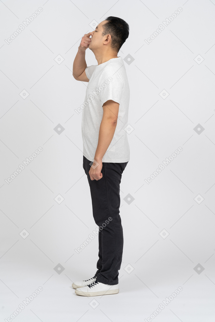 Side view of a man in casual clothes touching his nose