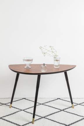 Glass vases with dried twig, perfume bottle on coffee table