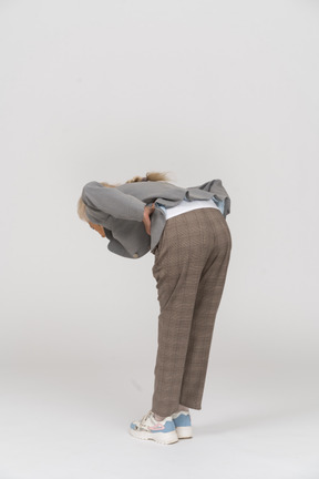 Side view of an old lady in suit bending down