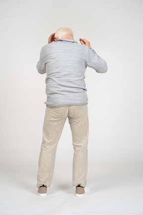 Back view of man reaching for the head with both hands