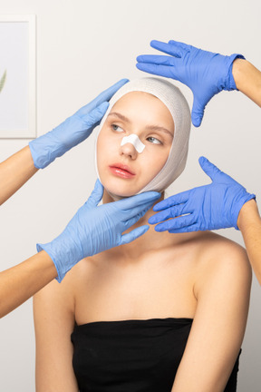 Young woman with head bandage surrounded by hands