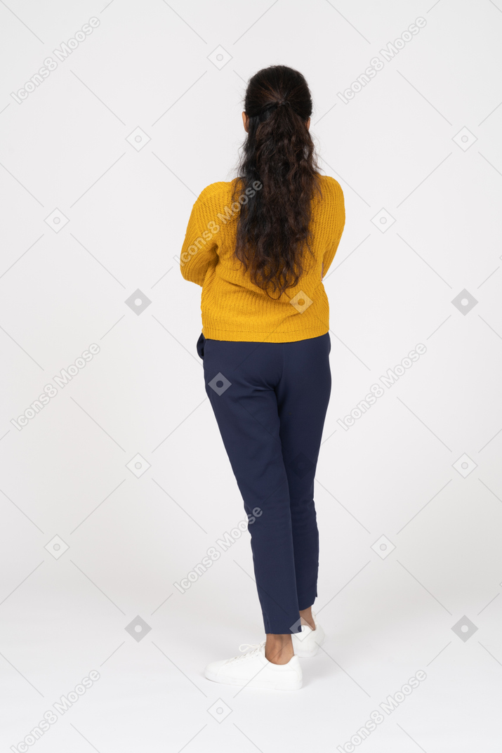 Vista posteriore di una ragazza in abiti casual in posa con le braccia incrociate
