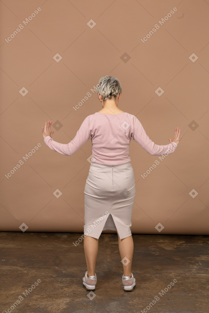 Вид сзади женщины в повседневной одежде, показывающей размер чего-то
