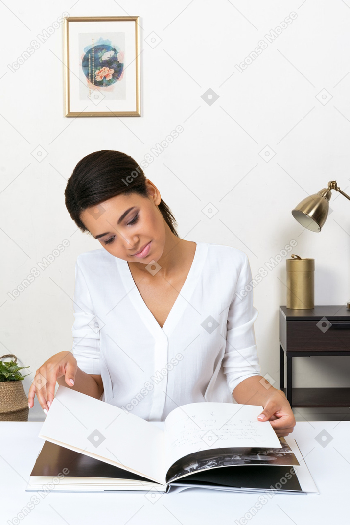 A woman sitting at a desk reading a book