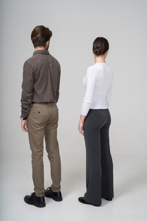 Three-quarter back view of a young couple in office clothing turning away