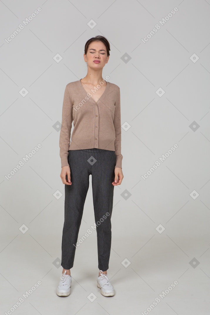 Vista frontale di una giovane donna in pullover e pantaloni in piedi con gli occhi chiusi