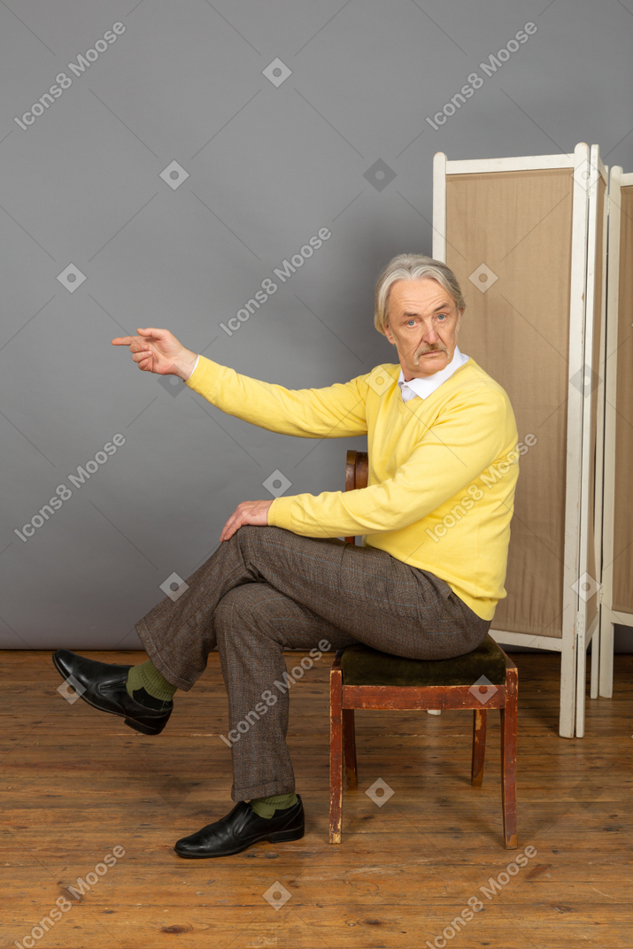 Man sitting on a chair and pointing left