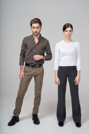 Front view of a young couple in office clothing standing still