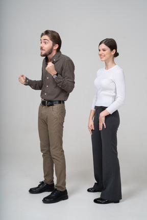 Three-quarter view of a delighted young woman and impatient man in office clothing