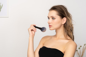 Three-quarter view of a sensual young woman holding a make-up brush