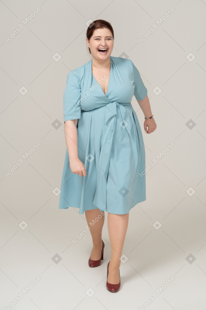 Vue de face d'une femme en robe bleue marchant
