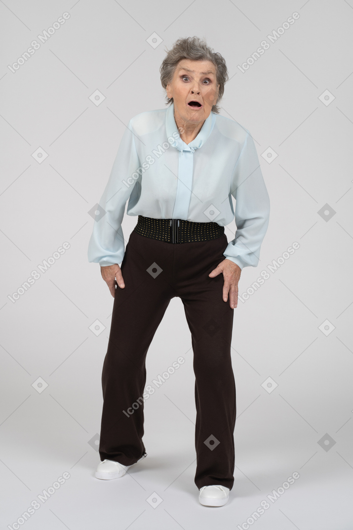 Front view of an old woman stepping forward looking shocked and panicked