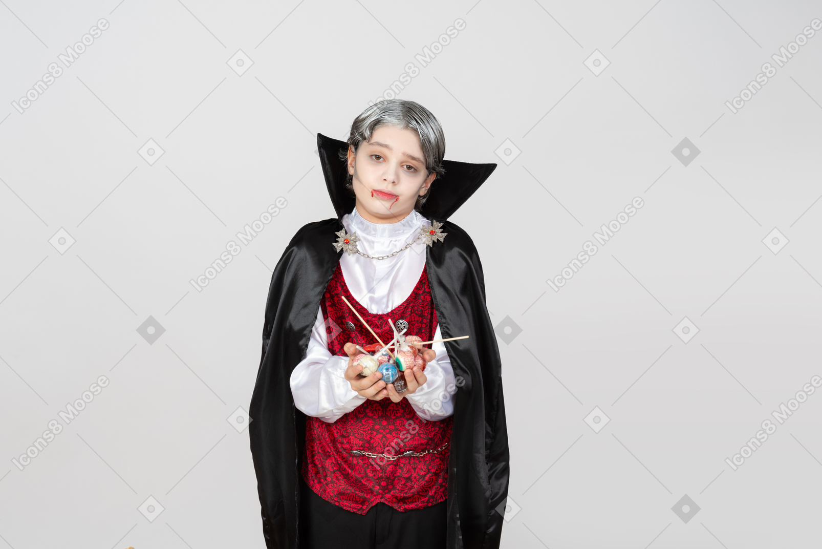 Niño disfrazado de vampiro sosteniendo caramelos