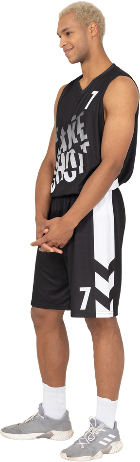 Three-quarter view of a shy young male basketball player holding hands together