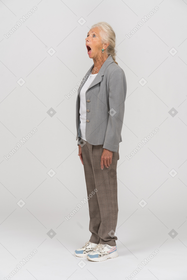 Side view of an old woman in suit standing with open mouth
