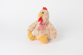 A plush chicken toy with a checkered bow, sitting isolated against a plain white background