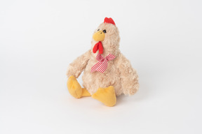 Un peluche de pollo con un arco a cuadros, sentado aislado contra un fondo blanco liso