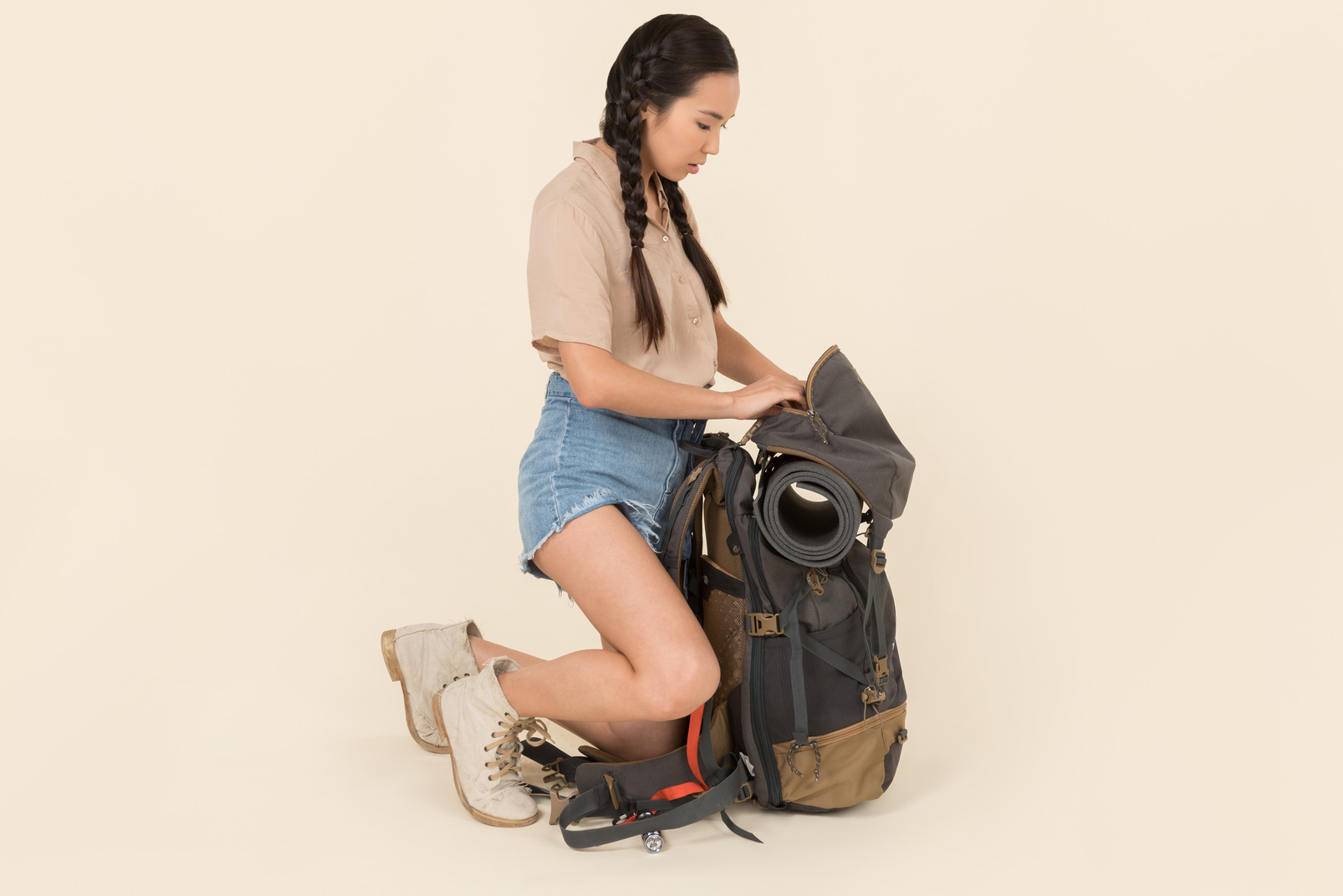 Young asian female traveller sitting near huge tourist backpack
