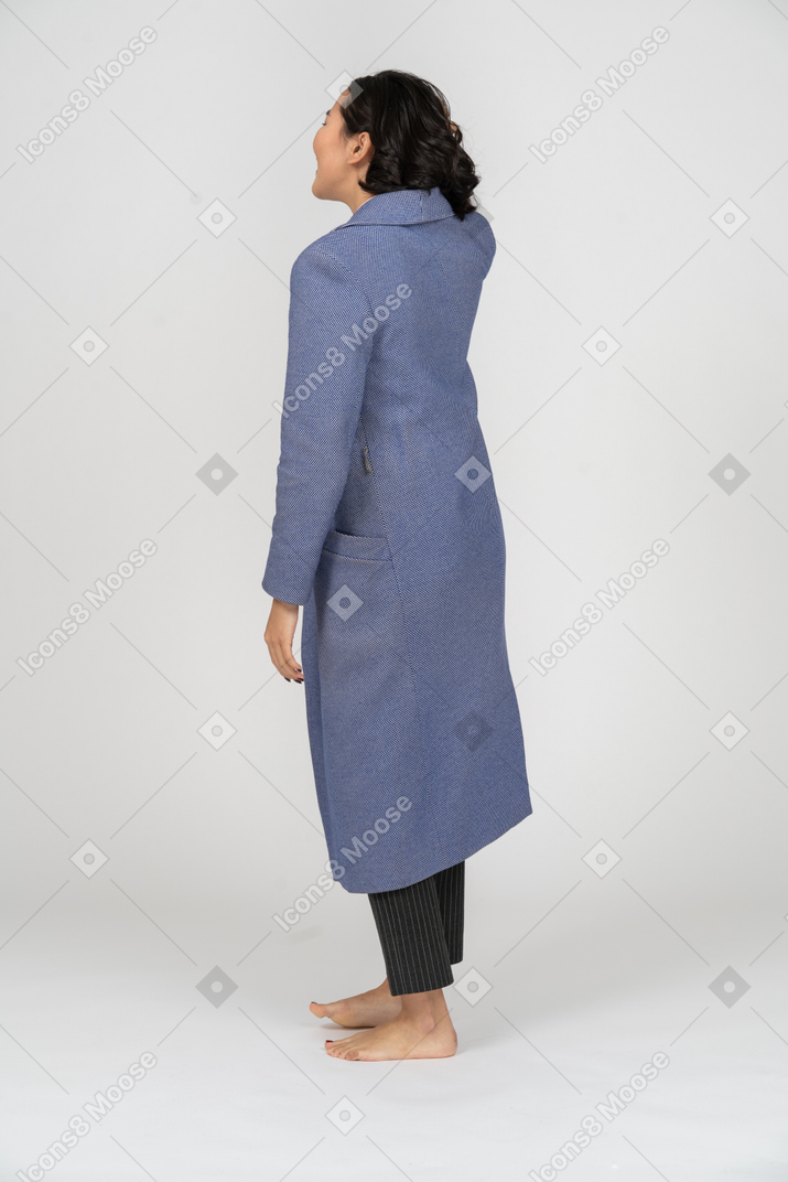 Vista traseira de uma mulher de casaco arrumando o cabelo