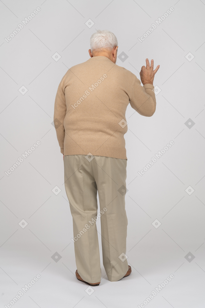 Okサインを示すカジュアルな服装の老人の背面図