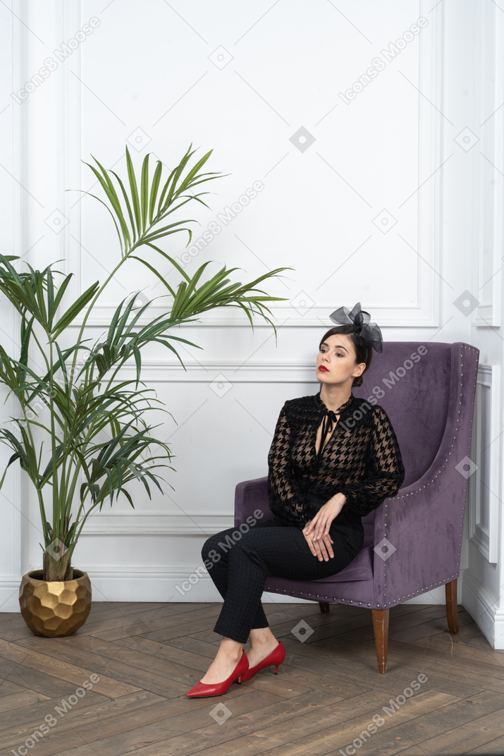 A woman sitting on a purple chair next to a potted plant