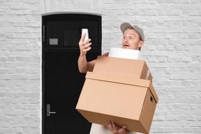 A man holding a cardboard box and a cell phone