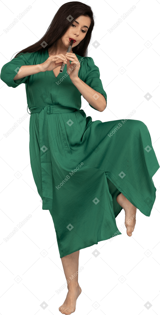 Vista frontal de uma jovem dançando com vestido verde tocando flauta