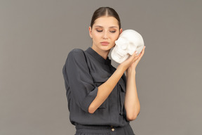 Front view of a young woman in a jumpsuit holding a plaster skull