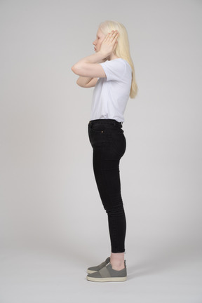 Side view of a young woman covering her ears